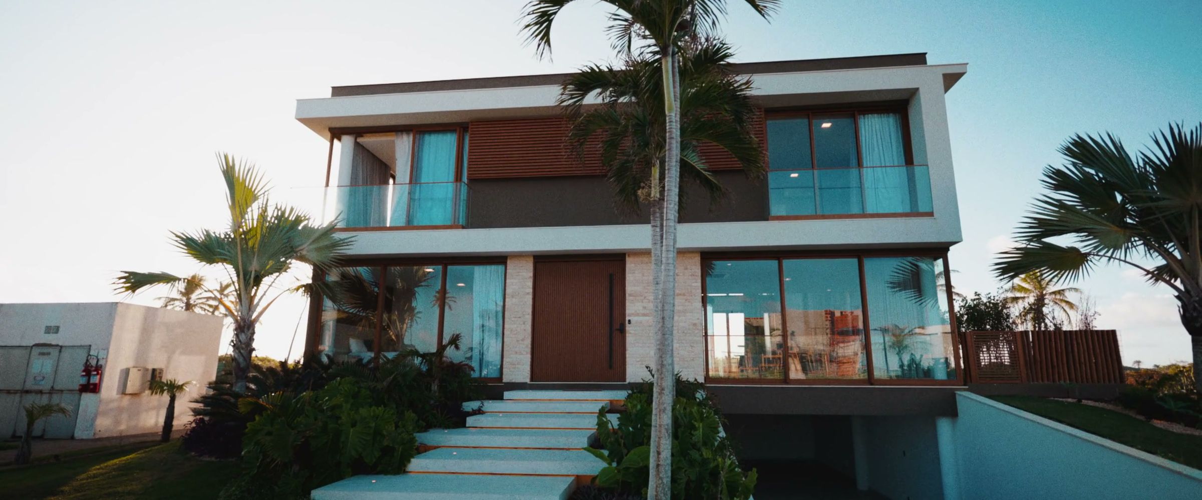 Modern two-story home with palm trees in front